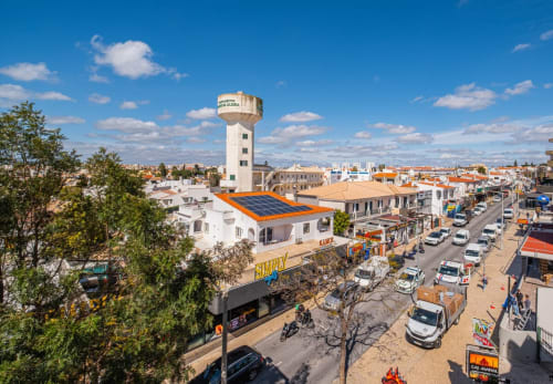 Vista aérea do edifício Heart of Oura com painéis solares na movimentada rua de Albufeira