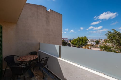 Terraço da varanda do apartamento Heart of Oura em Albufeira com assentos, guarda-corpo branco e vista da cidade sob céu azul