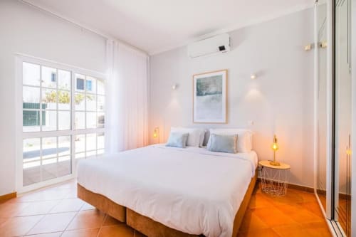 Quarto moderno e luminoso no apartamento SignatureStays Vicente Mar em Albufeira com cama king, acesso ao terraço e iluminação aconchegante