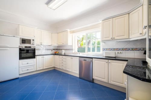 Cozinha espaçosa no apartamento SignatureStays Vicente Mar em Albufeira com armários creme, bancadas pretas e azulejos azuis
