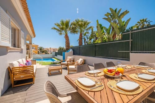 Terraço do apartamento Vicente Mar em Albufeira com mesa de jantar, piscina, palmeiras e vista para o mar