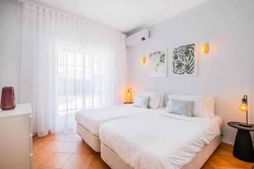 Quarto moderno no SignatureStays Vicente Mar em Albufeira com camas gêmeas, arte botânica e iluminação ambiente aconchegante