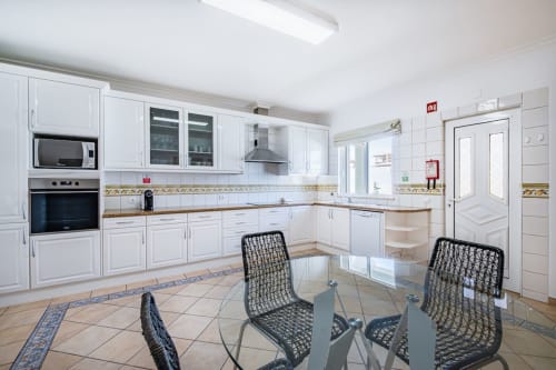 Cozinha moderna com armários brancos e área de refeições na Villa Rosal by SignatureStays, Albufeira