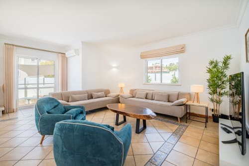 Espaçosa sala de estar moderna na Villa Rosal, SignatureStays Albufeira, com sofá seccional bege, poltronas azuis e luz natural