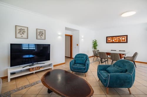 Sala moderna da Villa Rosal em Albufeira com poltronas turquesas, TV de tela plana e zona de refeições