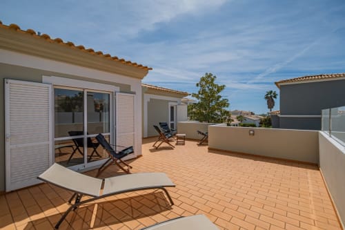 Terraço espaçoso na Villa Rosal em Albufeira com espreguiçadeiras, mesa e vista para o mar