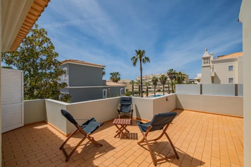 Terraço ensolarado da Villa Rosal em Albufeira com espreguiçadeiras, paredes brancas e vistas para o mar