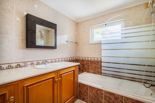 Banheiro moderno no apartamento Villa Rosal com móvel lavatório de madeira, painel decorativo em azulejo e chuveiro em vidro em Albufeira