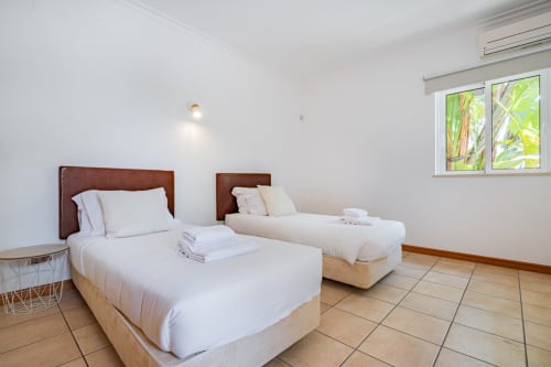 Quarto duplo da Villa Rosal by SignatureStays em Albufeira com duas camas, cabeceiras em madeira e vista para o jardim