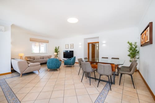 Sala de estar do apartamento moderno em Albufeira com sofá bege, mesa de jantar e detalhes em azul-teal na Villa Rosal