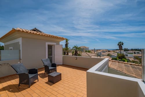 Amplo terraço na cobertura da Villa Rosal em Albufeira com espreguiçadeiras, vistas para o oceano e vilas vizinhas.