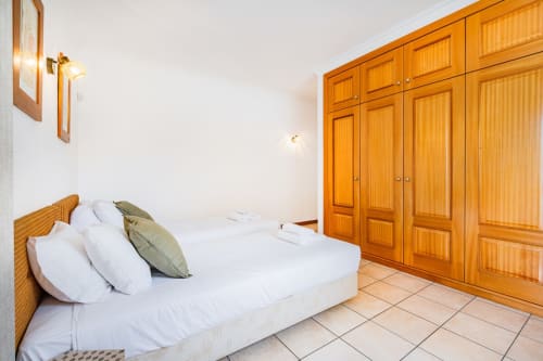Quarto moderno da Villa Rosal, apartamento SignatureStays em Albufeira com cama de madeira, roupa de cama branca e ampla janela