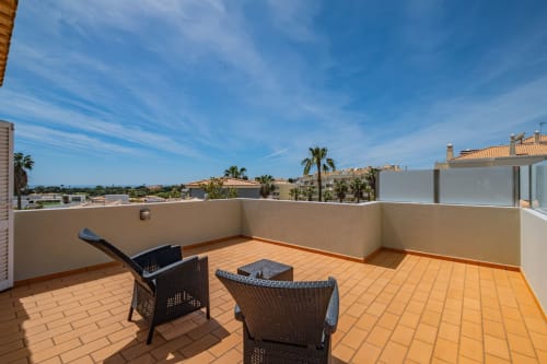 Terraço espaçoso na Villa Rosal em Albufeira com espreguiçadeiras, vista para o oceano e palmeiras
