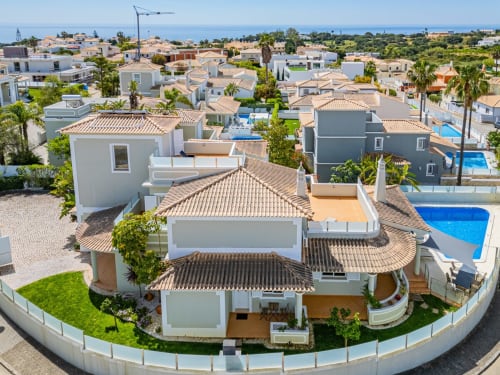 Vista aérea do apartamento Villa Rosal em Albufeira com paredes brancas, telhado de barro, piscina e jardins frente ao mar