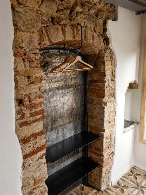 Begehbarer Ziegelspeicher mit Metallregalen und Holzbügeln im Bergamo-Apartment