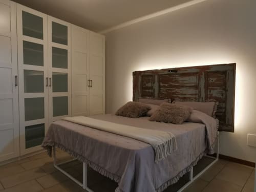 Modern bedroom at The Kraken Inn, Bergamo with rustic wooden headboard, built-in wardrobes, and ambient lighting