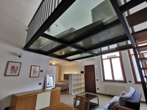 Modern loft apartment at The Kraken Inn, Bergamo with black steel ceiling beams, white walls, and contemporary furnishings