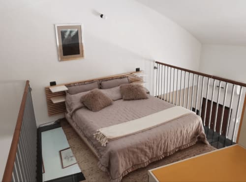 Cozy loft bedroom at The Kraken Inn in Bergamo with queen bed, wooden headboard, and mezzanine railing.