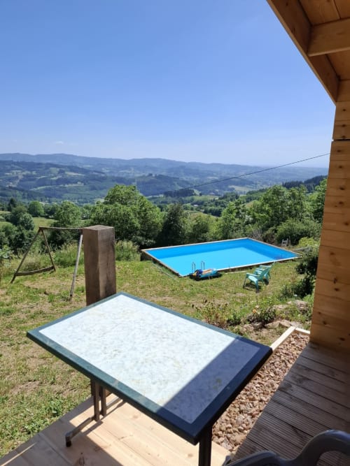 Blue pool overlooking rolling mountains at La Maison de Dun B&B in Saint Racho, France