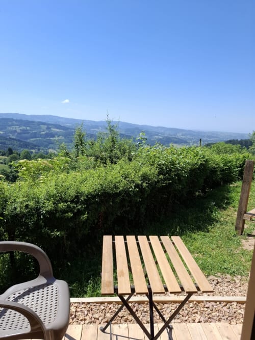 Wooden deck overlooking green vineyard rows and rolling mountains at La Maison de Dun, Saint Racho