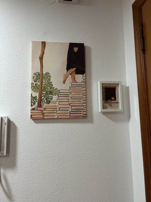 Arte minimalista en apartamento Houses by Pilar con figura sobre libros apilados y planta monstera, Arcade