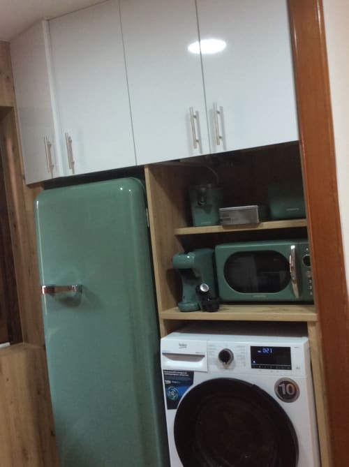 Cocina moderna con refrigerador retro verde menta, lavadora blanca, estantes de madera y electrodomésticos verdes en Houses by