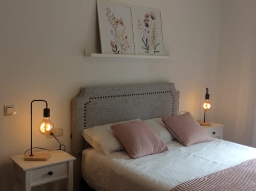 Acogedora habitación en Houses by Pilar, galería con cabecero tapizado gris, iluminación ambiental y arte botánico en la pared