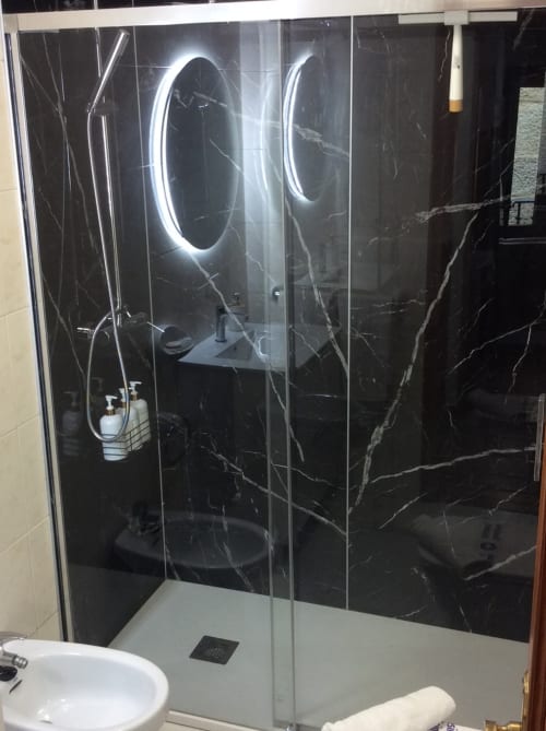 Moderno revestimiento de ducha en mármol negro con espejo iluminado en apartamentos Houses by Pilar de Arcade