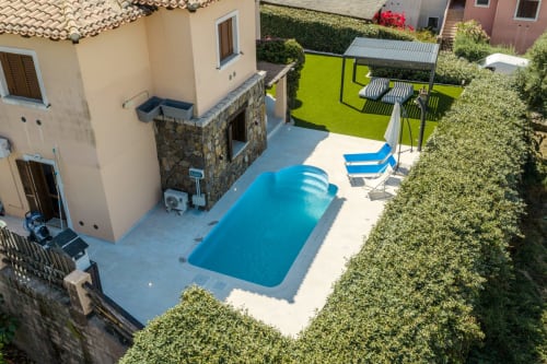Vista aerea della villa Poggio dei Fiori a Olba con piscina rettangolare blu, lettini e giardino curato