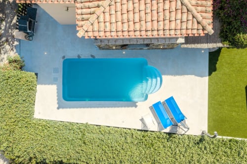 Vista aerea della piscina di Villa Poggio dei Fiori a Olbia con lettini e terrazza circondata da siepi verdi