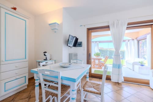 Luminosa sala da pranzo della villa Poggio dei Fiori a Olbia, con tavolo bianco, dettagli blu e vista sulla terrazza