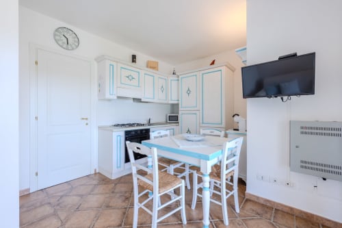 Cucina e zona pranzo moderne con mobili blu e bianchi, tavolo con sedie e TV a schermo piatto a Poggio dei Fiori