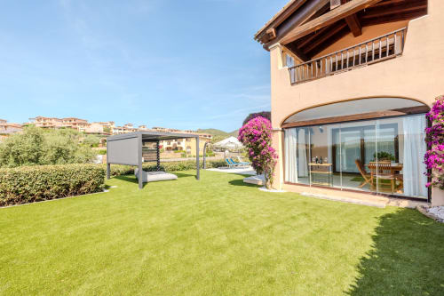 Villa Poggio dei Fiori a Olbia con prato curato, pergolato moderno e buganvillea fucsia vicino alla terrazza