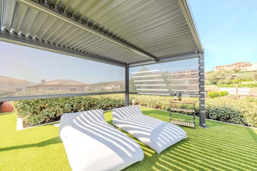 Terrazza con pergola moderna e lettini con vista su rigogliosi giardini presso villa Perseo Case Vacanze a Olba, Italia