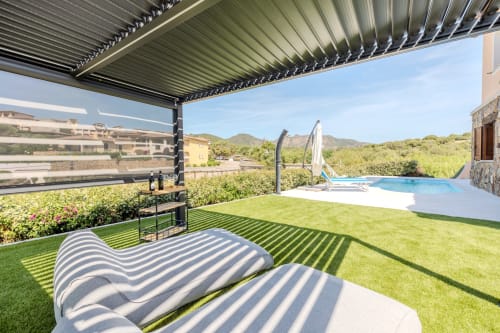 Lettini a righe su prato curato con pergola, piscina e vista montagna alla villa Poggio dei Fiori a Olbia
