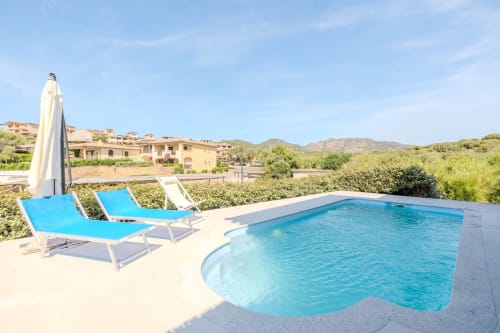 Villa Olbia con piscina, lettini blu, ombrellone e vista panoramica sulle montagne della Sardegna