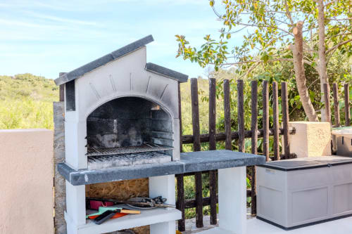 Forno per pizza esterno con zona grill presso la villa Poggio dei Fiori a Olbia, Italia, con struttura bianca e pietra scura