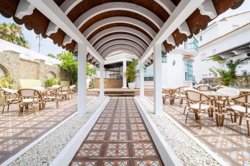 Pasillo con pérgola cubierta y vigas de madera arqueada en Hotel Boutique Zahara, con baldosas de terracota y zonas de descanso