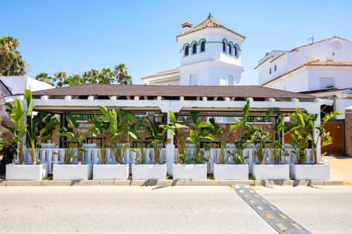 Restaurante frente al mar del Hotel Boutique Zahara con pérgola blanca, plantas tropicales y arquitectura de torre marroquí