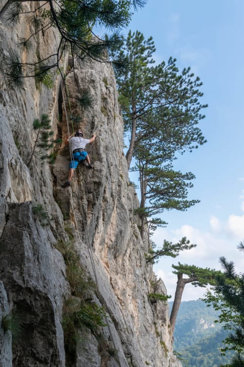 Grimpeur escaladant une paroi rocheuse abrupte près de la vallée du Doubs, France, activité d'aventure en plein air