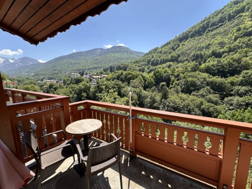 Balcon en bois avec vue sur les montagnes à l'Hôtel Studios La Rochetaillée à Brides-les-Bains, table à manger et forêt