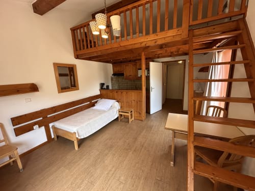 Studio Confort Mezzanine de l'Hôtel Studios La Rochetaillée à Brides-les-Bains avec mezzanine en bois, lit et kitchenette