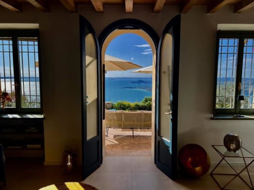 Gewölbter Eingang der Villa Blu mit Blick auf den Gardasee in Salò. Innenraum mit Holzbalken, blauen Türen und Terrassenzugang.