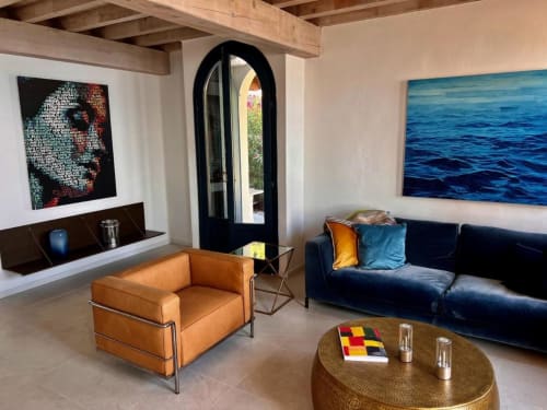 Wohnzimmer der Villa Blu im Prince Garda Salò mit orangefarbenem Sessel, dunkelblauem Sofa und Seeblick durch Rundbogentür