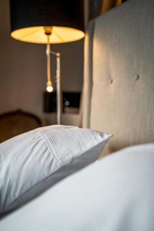 Lit avec oreiller rayé et lampadaire lumineux dans la suite Les Jardins de Babylone de l'hôtel d'Avignon