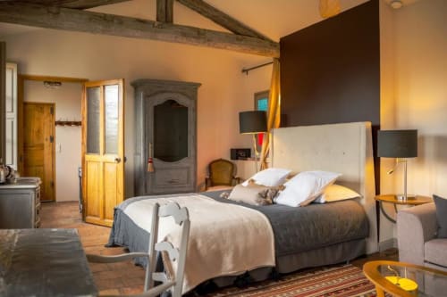 Suite Les Jardins de Babylone aux Jardins de Baracane à Avignon, lit aux oreillers blancs et poutres en bois