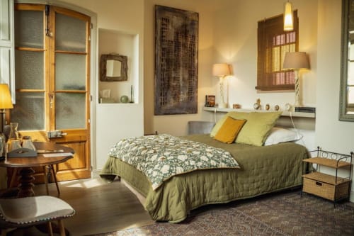 Chambre lumineuse aux Jardins de Baracane Avignon avec literie vert olive, accents jaunes et mobilier bois chaleureux.