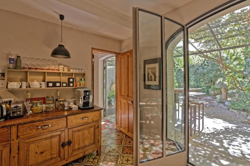 Cuisine rustique avec mobilier en bois, étagères ouvertes et portes vitrées ouvrant sur le jardin aux Jardins de Baracane, Avignon