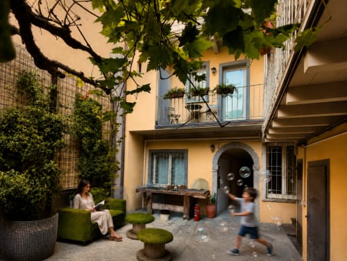 Charmanter Innenhof der Apartments Borgovivobg in Bergamo mit gelben Gebäuden, efeubedeckten Mauern und Außensitzbereich