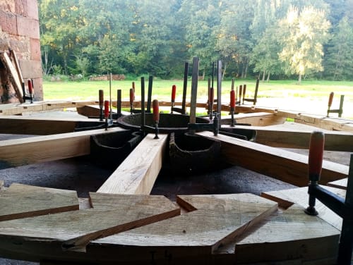 Atelier traditionnel de construction de bateaux en bois à la maison d'hôtes Paulusmühle à Soucht, France, avec la forêt en arrière-plan